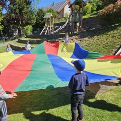 Kinder spielen auf dem Außengelände mit einem Schwungtuch