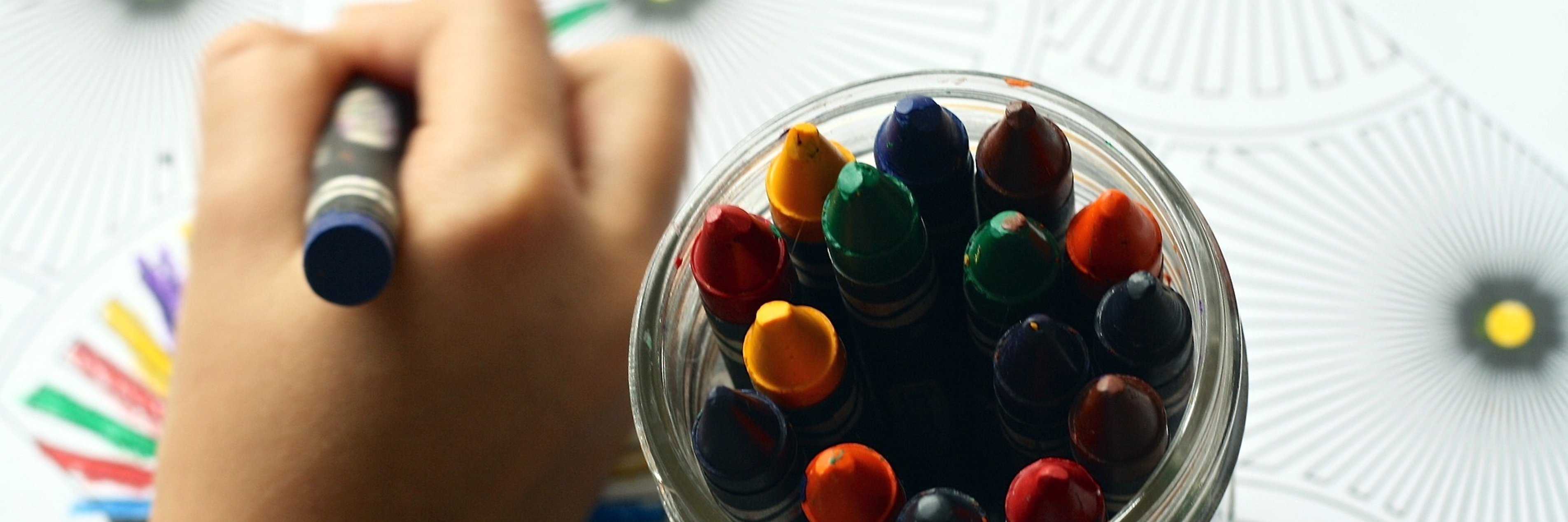 Kinderhand malt mit Wachsmalstiften